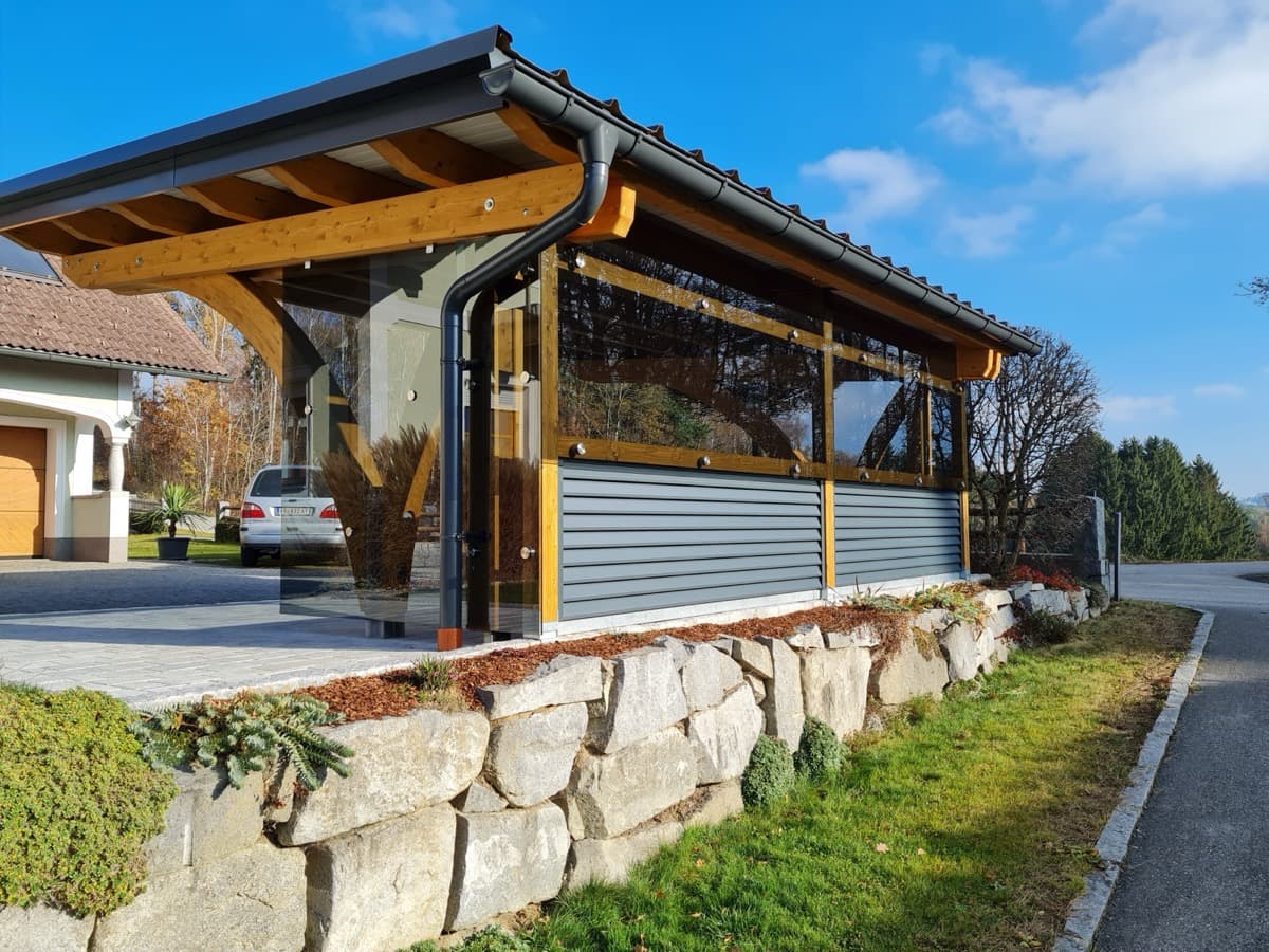 Carport mit Holzbögen, Lamellenwand und Steinmauer
