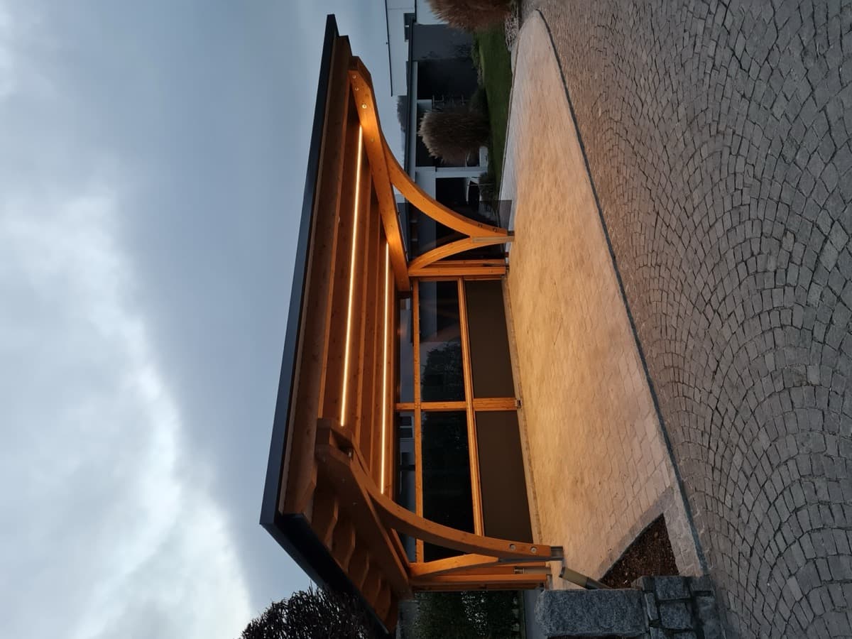 Beleuchteter Holz-Carport mit Bogenstützen in Abenddämmerung