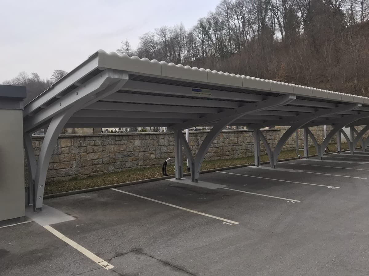 Metall-Reihencarport mit grauer Bogenkonstruktion auf Parkplatz