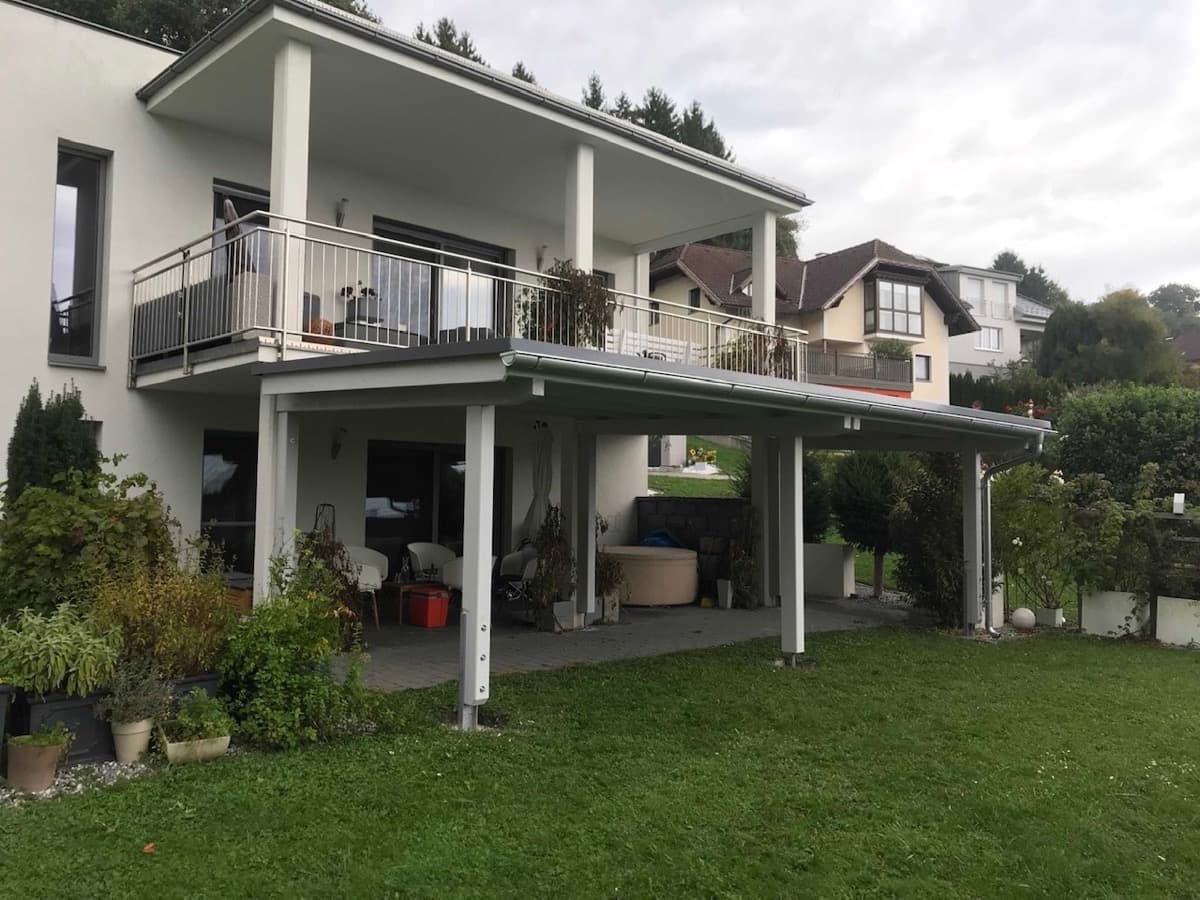 Moderner Carport mit Flachdach unter Balkon im Garten