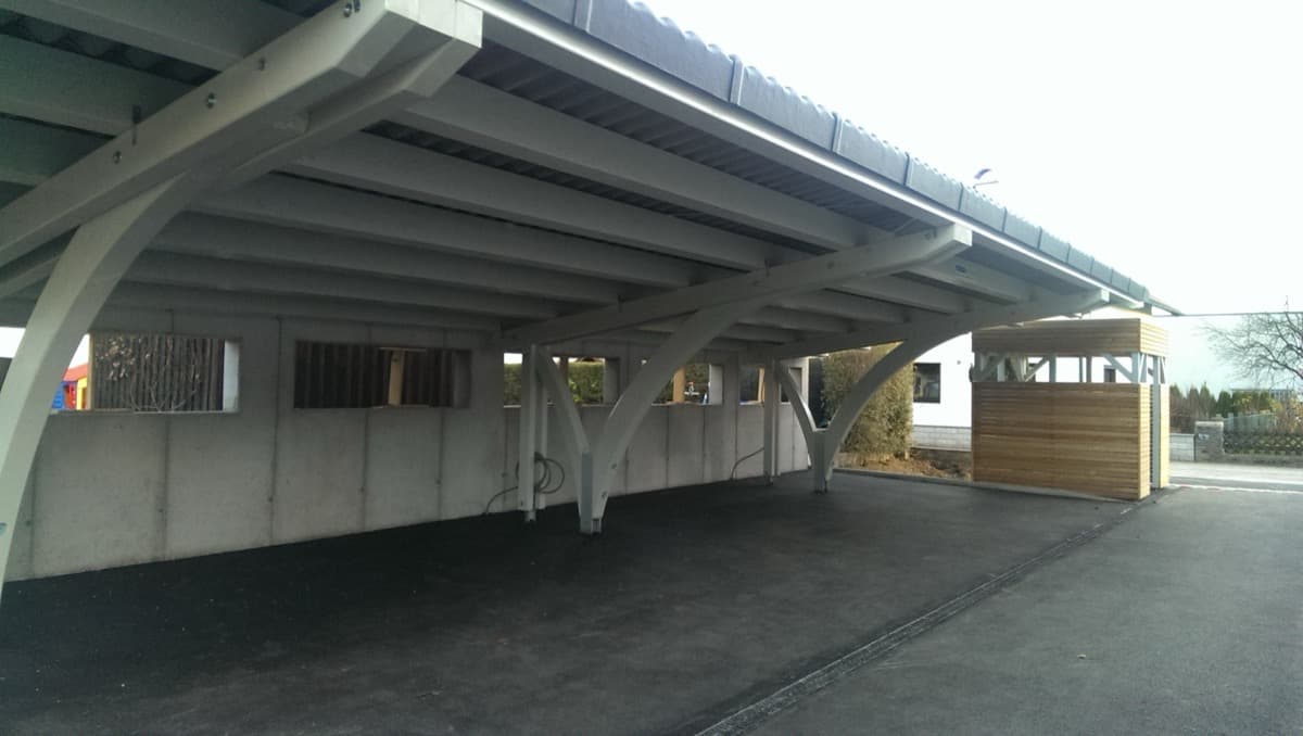 Großer Reihencarport mit weißen Bogenstützen und Holzgerätehaus