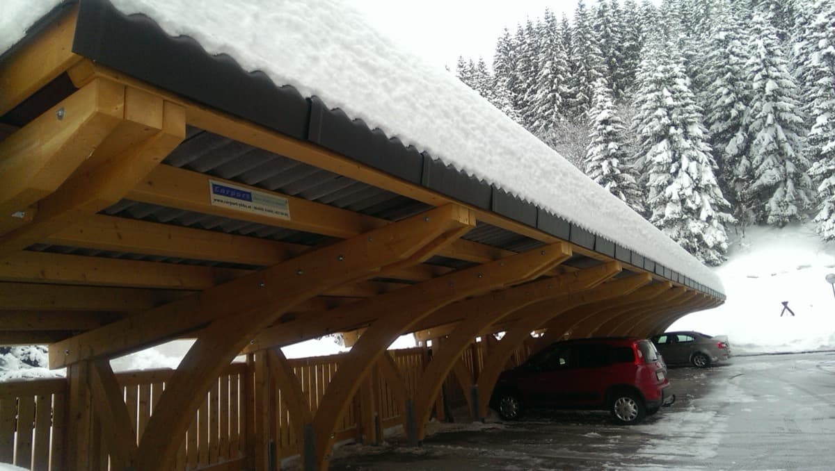 Holz-Reihencarport mit Bogenkonstruktion im verschneiten Berggebiet