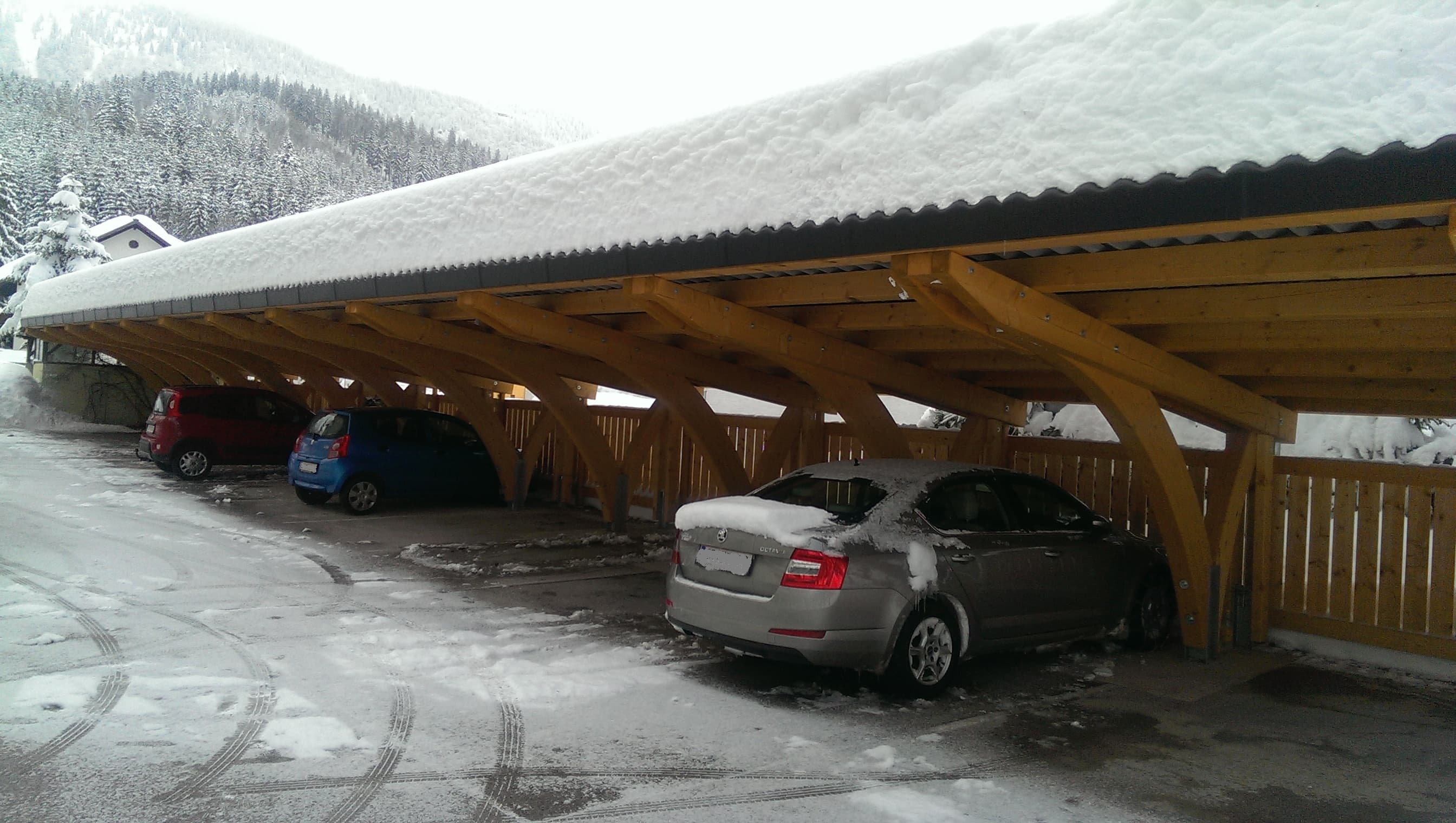 Reihen-Carport mit Bogenstützen und Schnee, Bergpanorama im Hintergrund