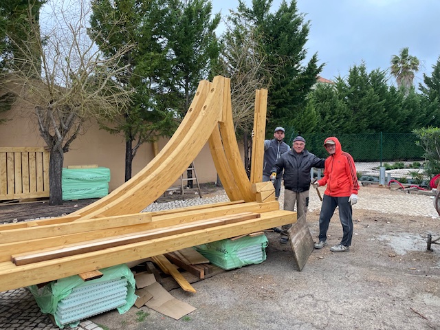 Monteure präsentieren angelieferte Carport-Bogenbinder vor der Montage