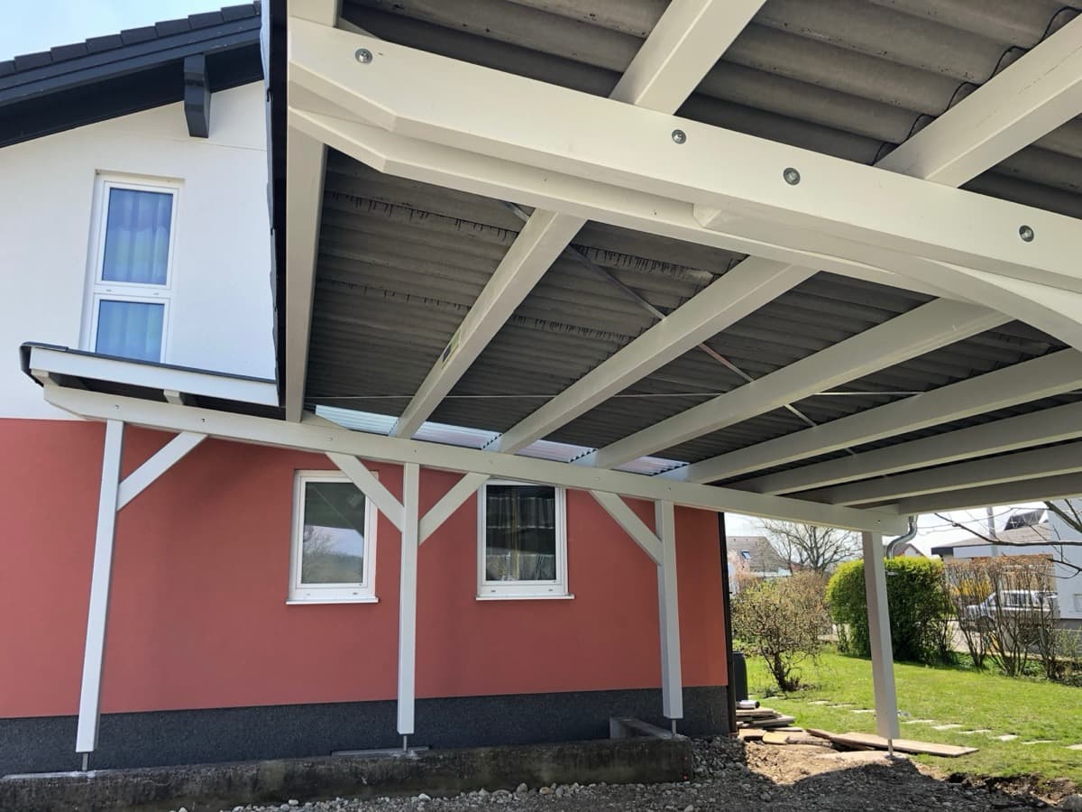 Weißer Carport mit Pultdach an Hauswand montiert
