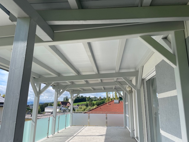 Weiße Terrassenüberdachung von unten mit Glasgeländer und Fernblick