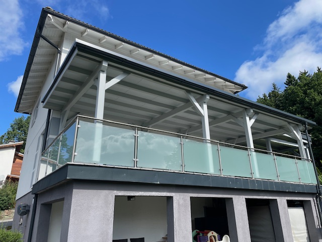 Weiße Terrassenüberdachung mit Glasgeländer am Hanghaus